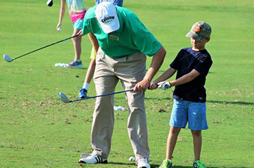 instructor guiding student with club swing
